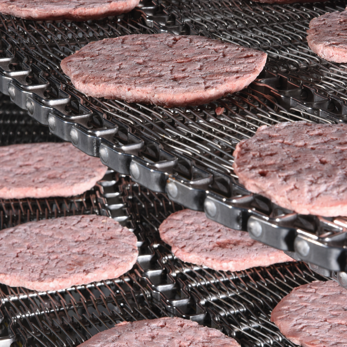 Ashworth Spiral Freezer Conveyor with raw burger patties sitting on the conveyor belt