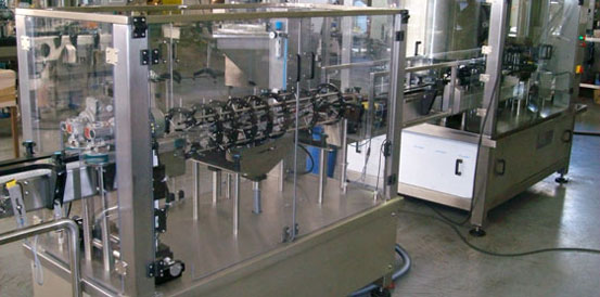 AR SERIES - LINEAR RINSERS.A Filtec bottling machine in a factory, featuring metal and glass enclosures, conveyor belts, and automated components for efficiently filling and packaging bottles.